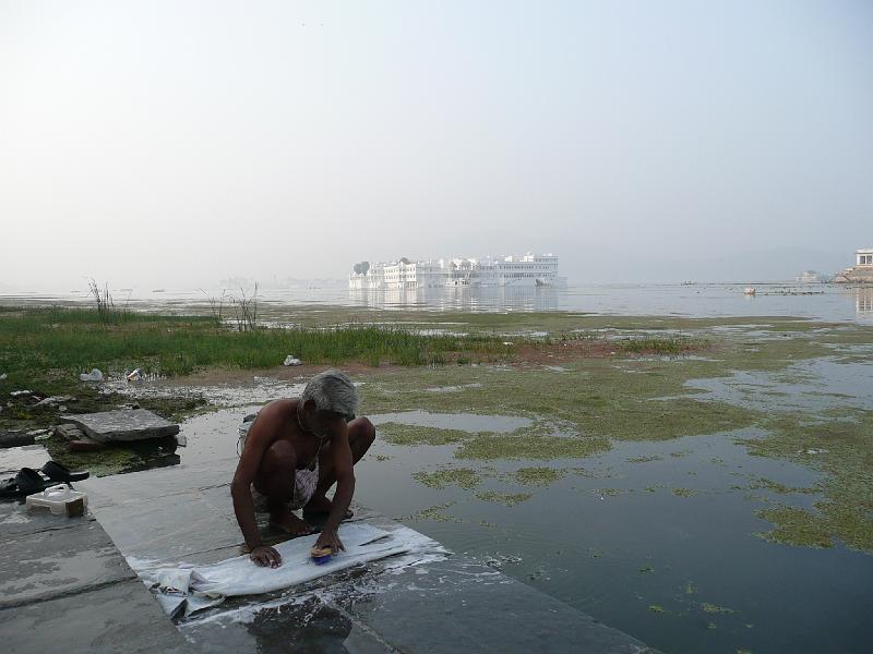 P1060444- Homme lavant son linge et lake palace hotel en arriere plan .JPG - Homme lavant son linge au bord du lac pichola et lake palace hotel (hotel de luxe) en arrière plan